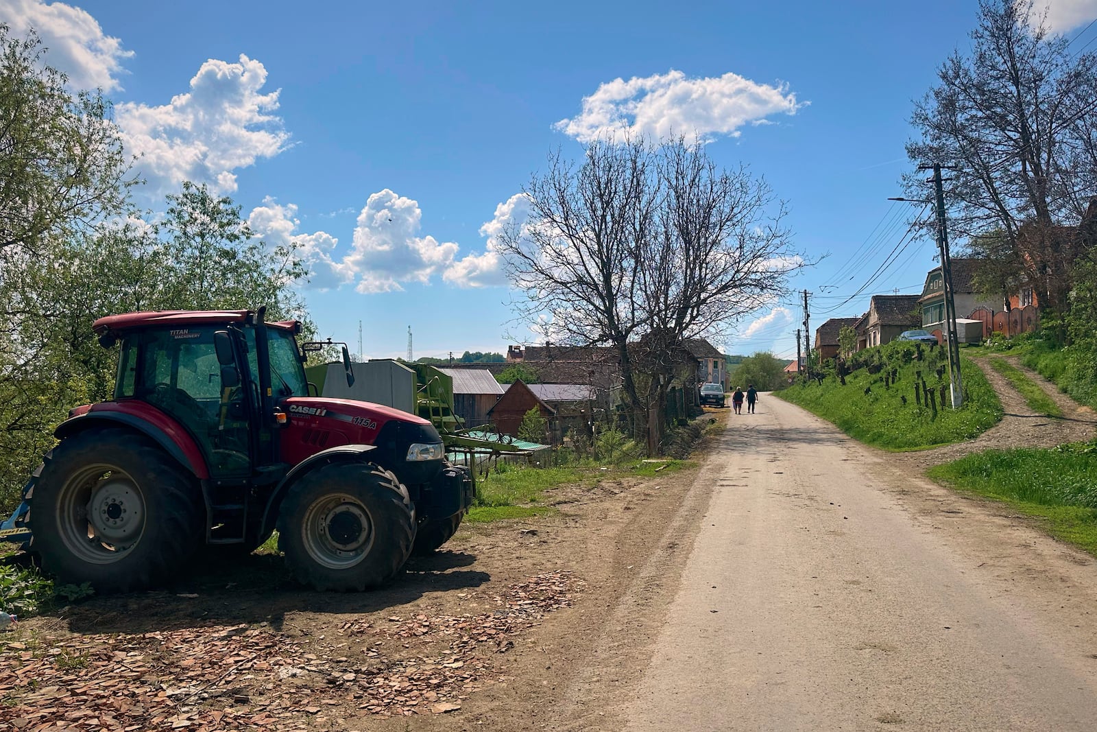 People walk on a road in the village of Saschiz, in Romania's central Transylvania region, Friday, April 25, 2025. (AP Photo/Stephen McGrath)