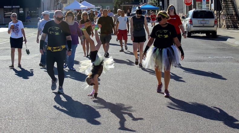 Batgirl Katelyn Patterson does a cartwheel during the one-mile walk while her parents, Charles and Beth Patterson, watch at last year's the Day in Wellville event. MICHAEL COOPER/STAFF