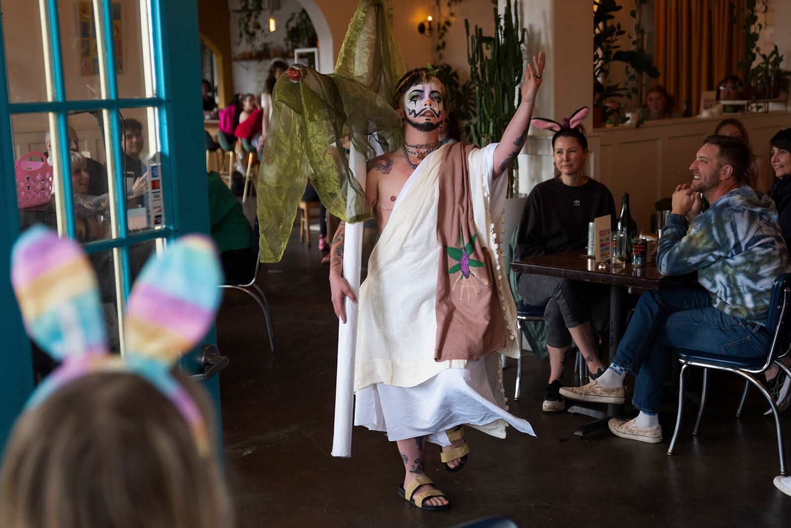 Drag performer Ed Du'Bull walks with a cross made to look like lit joints as he performs during a "blaze and praise" drag brunch at Bar Carlo on Sunday, April 20, 2025, in Portland, Ore. (AP Photo/Jenny Kane)