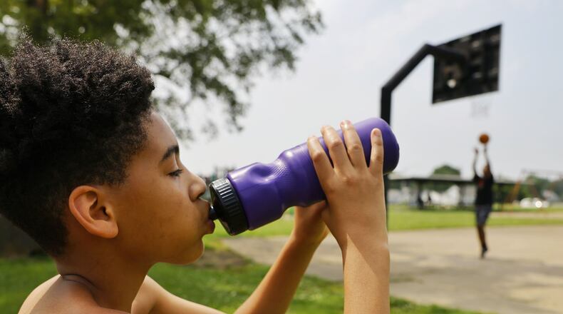 Izaiah Quinn, 11, takes a drink of water to cool off while playing basketball at Goldman Park Monday, June 13, 2022 in Middletown. NICK GRAHAM/STAFF