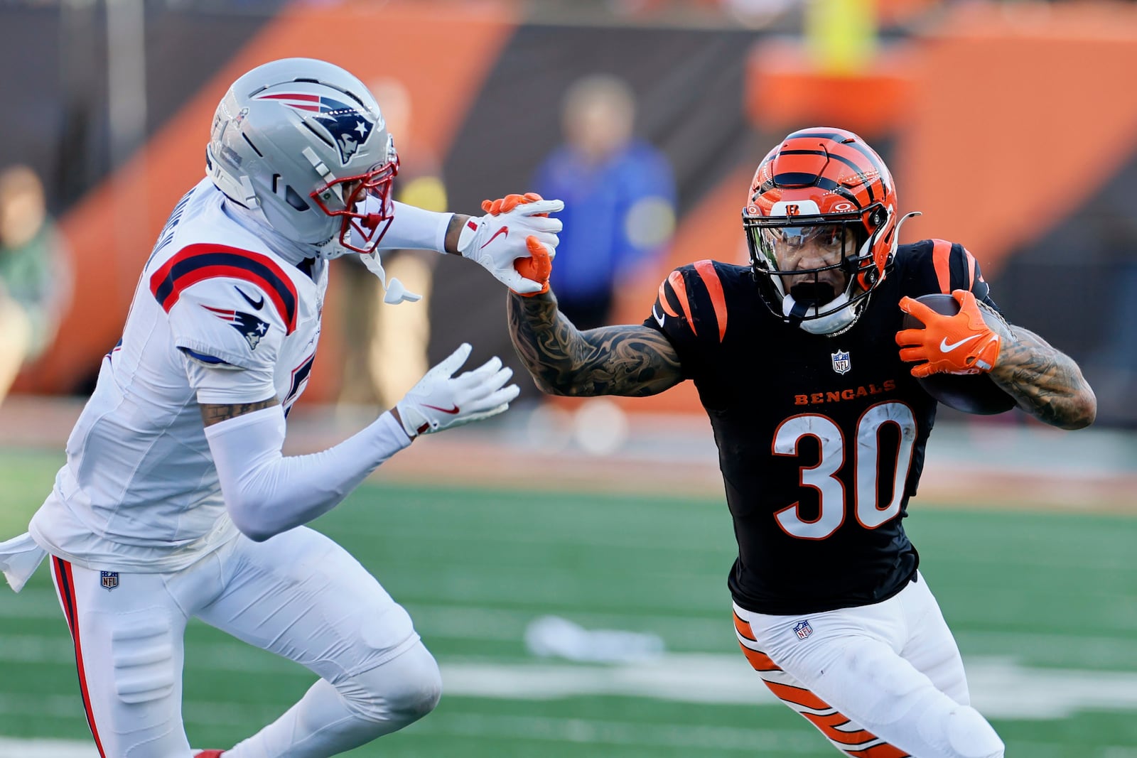 Cincinnati Bengals running back Chase Brown (30) runs from New England Patriots cornerback Carlton Davis III (7) during the first half of an NFL football game, Sunday, Nov. 23, 2025, in Cincinnati. (AP Photo/Jay LaPrete)