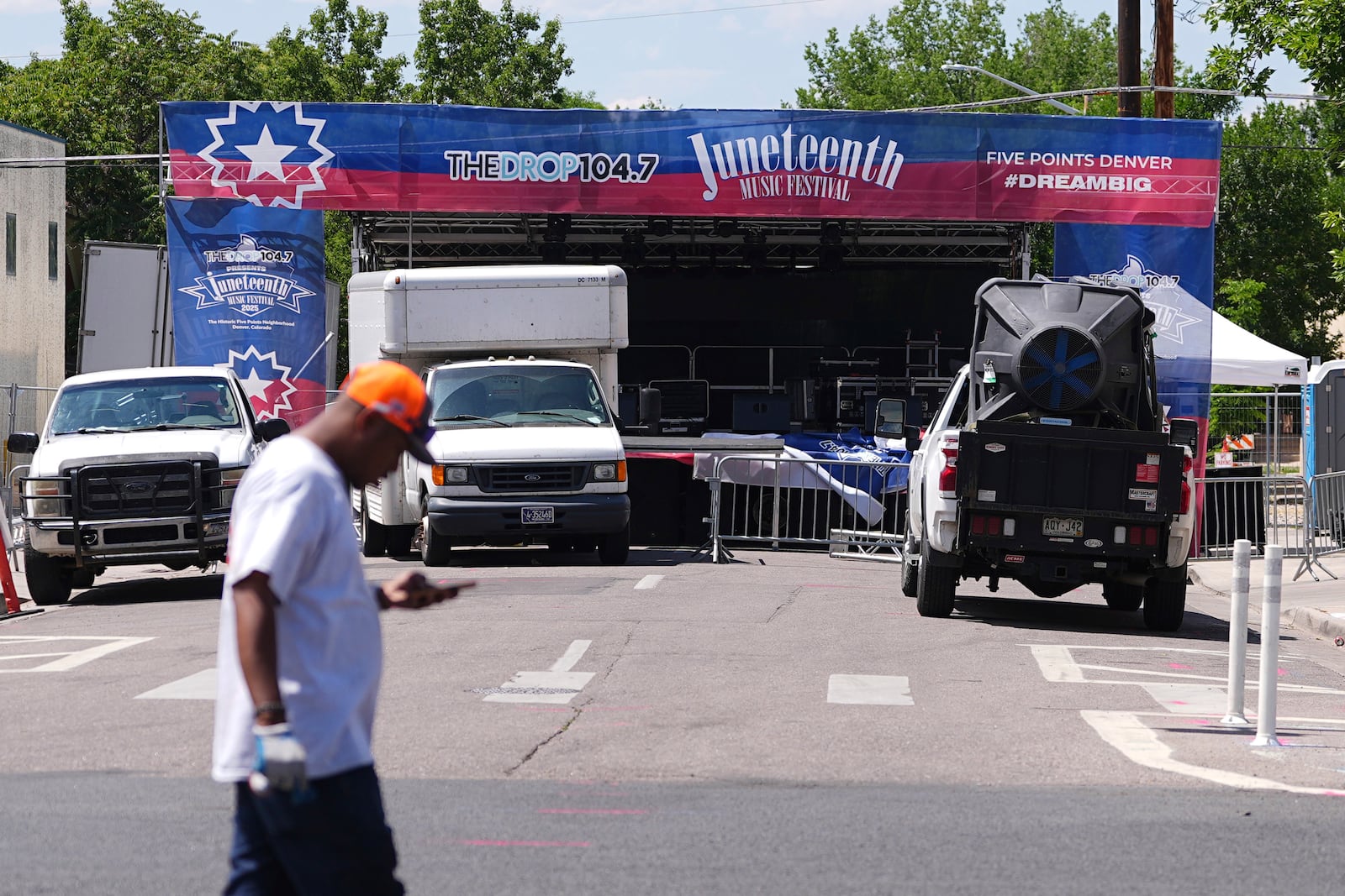 Volunteer passes by the stage for musical acts to perform at the Juneteenth celebration in the Five Points neighborhood where the event is staged Saturday, June 14, 2025, in Denver. (AP Photo/David Zalubowski)