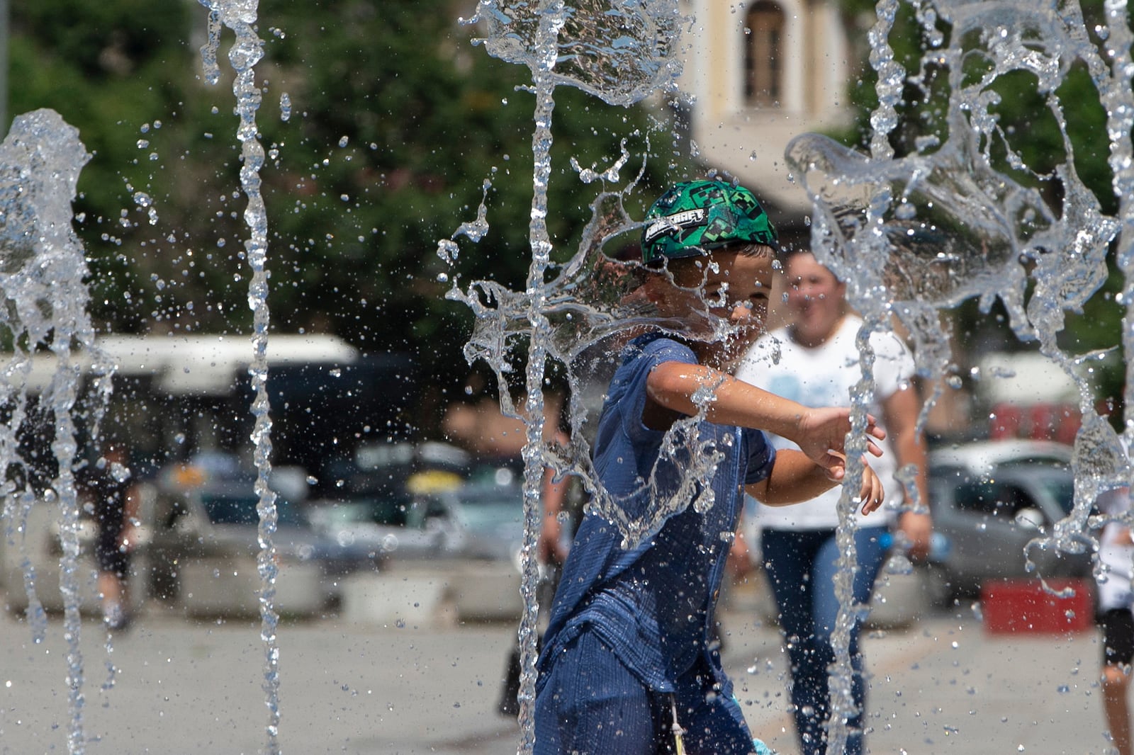 A boy plays in a fountain during hot weather in Kosovo's capital Pristina on Thursday, July 3, 2025. (AP Photo/Visar Kryeziu)