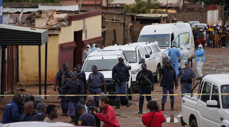 South African police gather at the scene of a mass shooting where gunmen killed nine and injured at least 10 in a pub in Bekkersdal, South Africa, Sunday, Dec. 21, 2025. (AP Photo/ Alfonso Nqunjana)