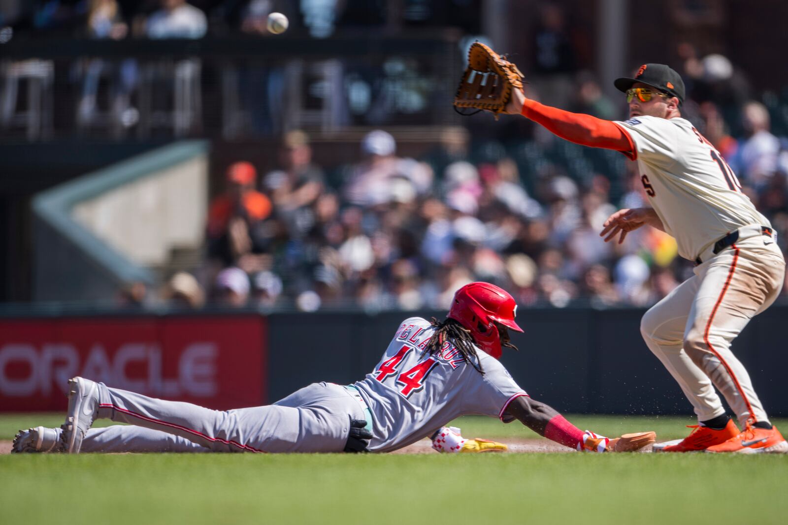 Cincinnati Reds' Elly De La Cruz (44) slides into first base after a pickoff attempt as San Francisco Giants first baseman Casey Schmitt catches the ball during the seventh inning of a baseball game in San Francisco, Wednesday, April 9, 2025. (AP Photo/Nic Coury)