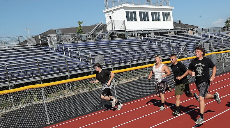 Senior football players at Mechanicsburg High School run past the empty bleachers at the school’s stadium Thursday. With the Coronavirus pandemic, its not clear if fans will be in the stands for games this season. BILL LACKEY/STAFF