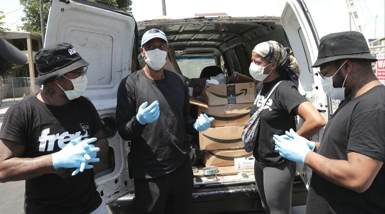 Dr. Armen Henderson, second from left, talks with volunteers Friday, April 3, 2020, before heading out to do outreach, including COVID-19 testing, with the homeless population in the Overtown neighborhood of Miami. Henderson, 34, was detained and handcuffed by a Miami police sergeant in front of his own home a week later, in an incident caught on video.