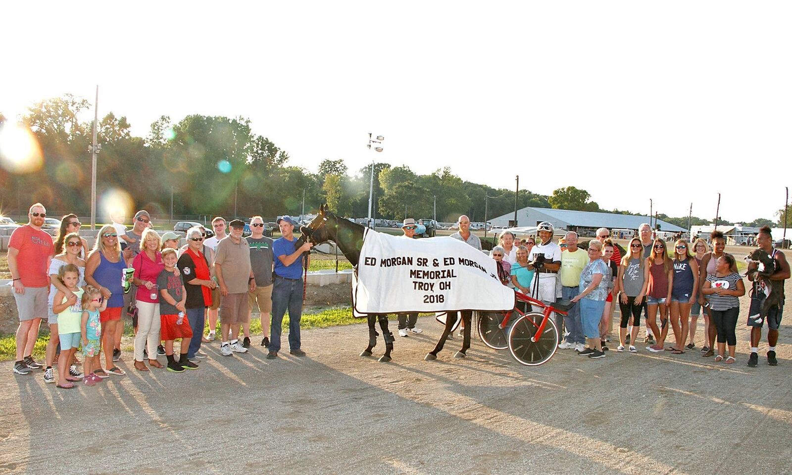 Tony Morgan (in drivers silks and helmet to right of Bold Decision) surrounded by family and friendin the Winners Circle after he won the Eddie Morgan Sr./ Eddie Morgan Jr Memorial at Miami County Fairgrounds on Monday night. Ben Holton/Conrad Photo