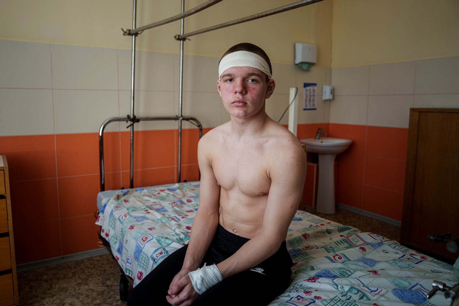 Kyrylo Illiashenko, 13, sits on a hospital bed, Monday, April 14, 2025, after being injured on Sunday by a Russian missile strike on Sumy, Ukraine, while trying to help others evacuate a burning bus that he later exited through a shattered window. (AP Photo/Evgeniy Maloletka)