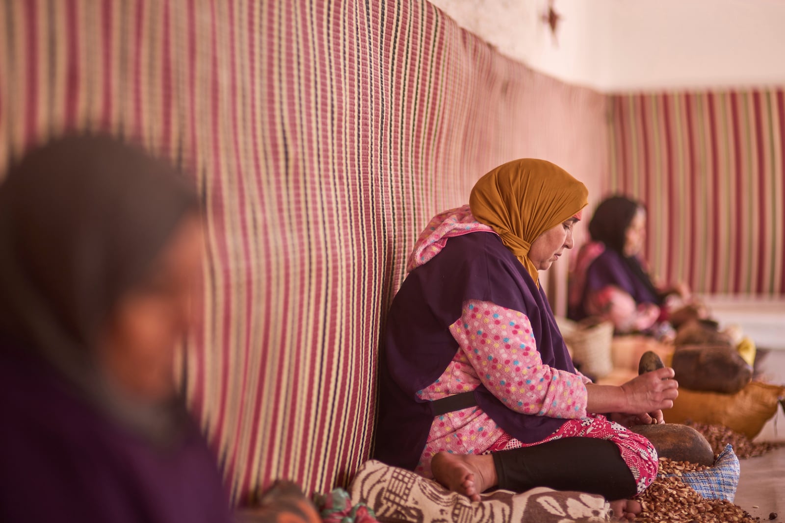 Women crack argan nuts at a cooperative that extracts and produces argan oil and products, in Essaouira, Morocco, Thursday, May 22, 2025. (AP Photo/Mosa'ab Elshamy)