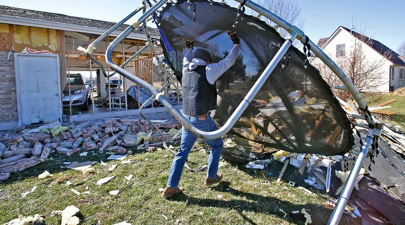 Jake Martin flips a broken trampoline onto a garbage pile as he helps his brother, Andy, clean up his yard Thursday, Feb. 29, 2024. Andy's house was one of several damaged by the tornado Wednesday morning along Mitchell Road. BILL LACKEY/STAFF
