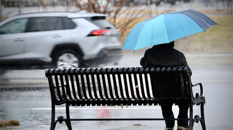 Trying to stay dry while waiting for a bus on Wilmington Pike in Kettering Thursday, Feb. 17, 2022. MARSHALL GORBY \STAFF