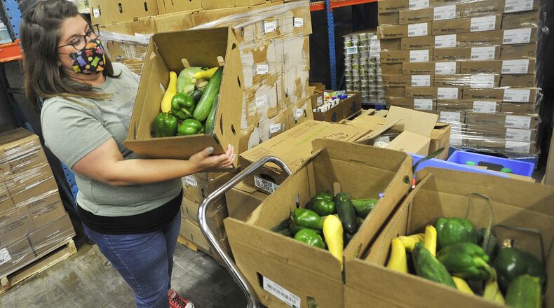 Lee Lauren Truesdale, the Chief Development Officer, for The Foodbank, moves boxes of fresh product in the cooler. The Foodbank started to receive thousands of boxes of produce, meat and dairy through a federal program. MARSHALL GORBYSTAFF