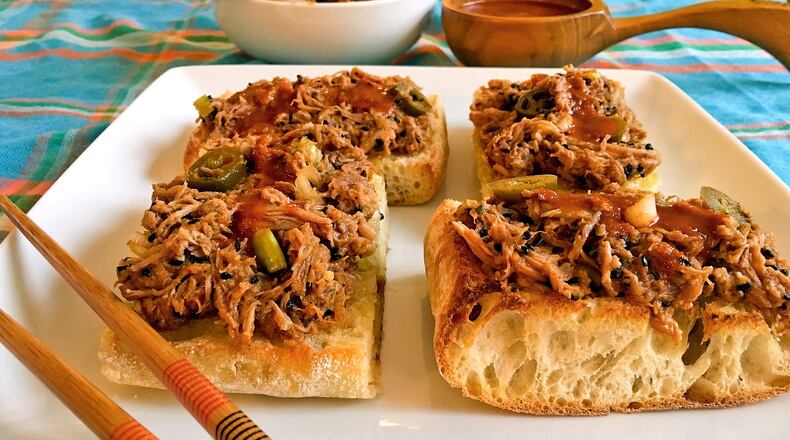 Korean-style Pulled Pork Pizza with a ladle of extra spicy sauce and a bowl of extra pork flanking the square plate of four pieces of pizza. (Karen Kane/ Pittsburgh Post-Gazette /TNS)