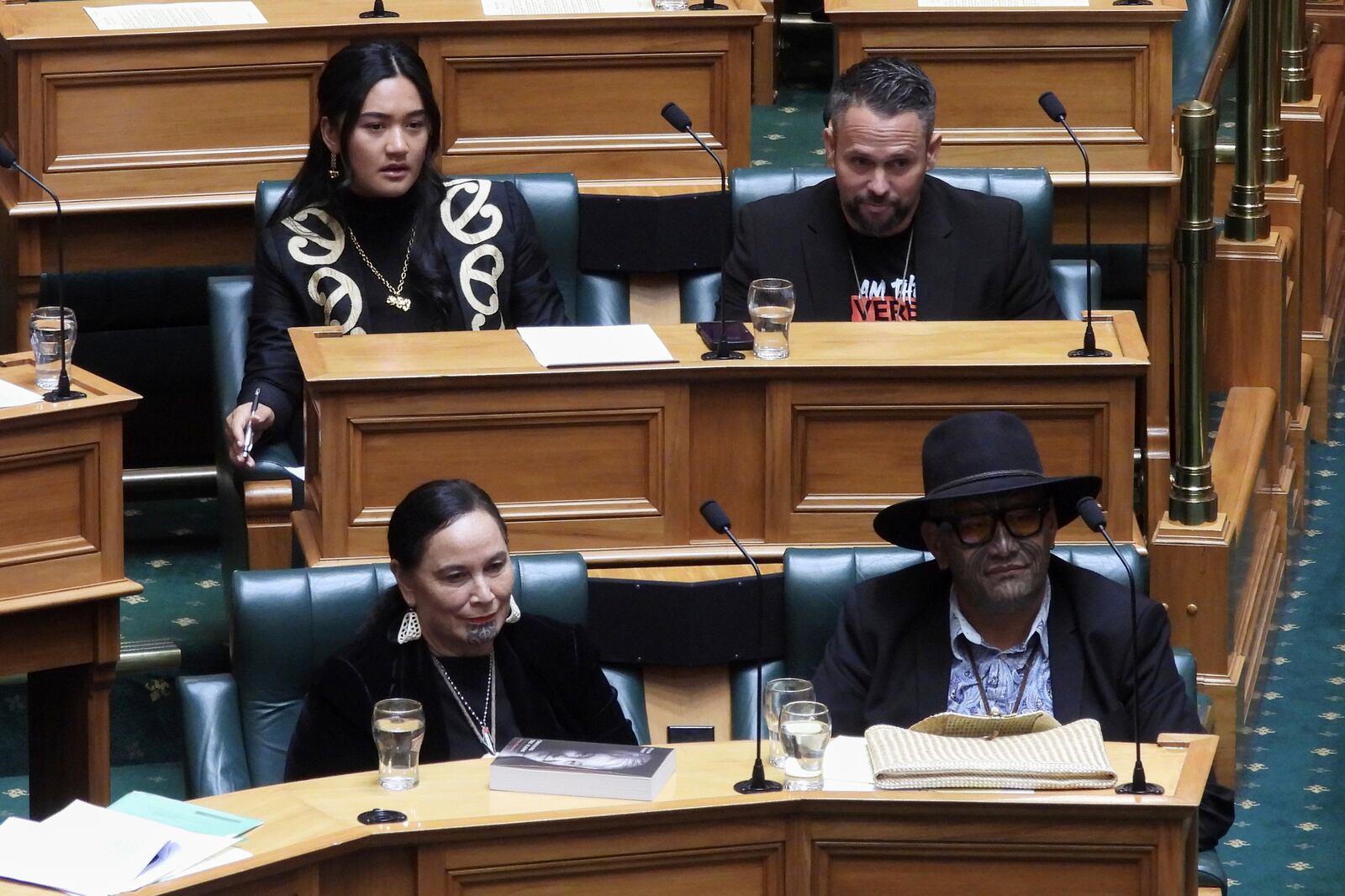 New Zealand lawmakers Hana-Rāwhiti Maipi-Clarke, top left, Debbie Ngarewa-Packer, bottom left, and Rawiri Waititi, bottom right, watch as other legislators debate their proposed bans in parliament in Wellington on Thursday, June 5, 2025. (AP Photo/Charlotte Graham-McLay)