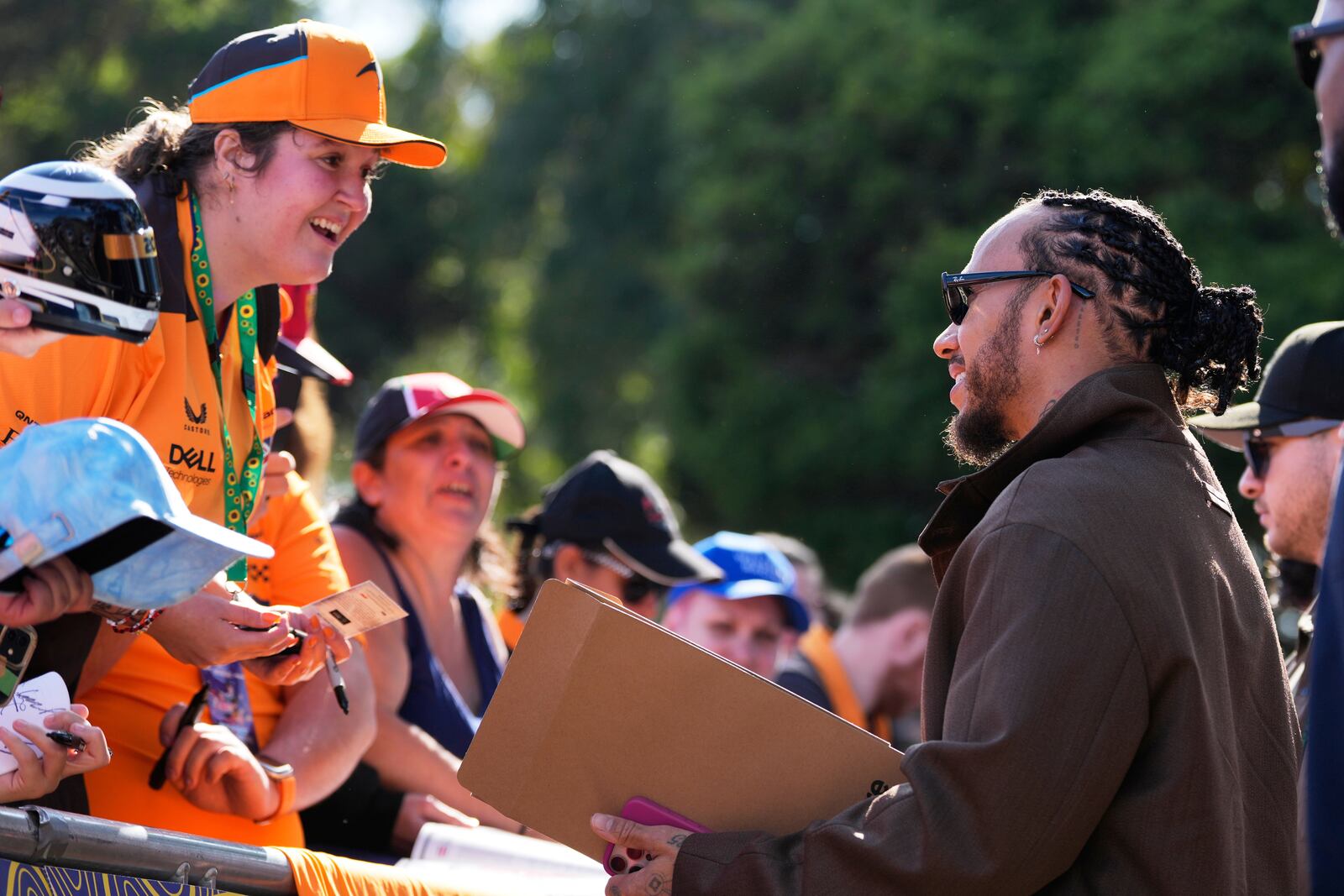 FILE - Ferrari driver Lewis Hamilton of Britain reacts with fans as he signs autographs as he arrives at the track ahead of the Australian Formula One Grand Prix at Albert Park, in Melbourne, Australia, Friday, March 14, 2025. (AP Photo/Asanka Brendon Ratnayake, File)