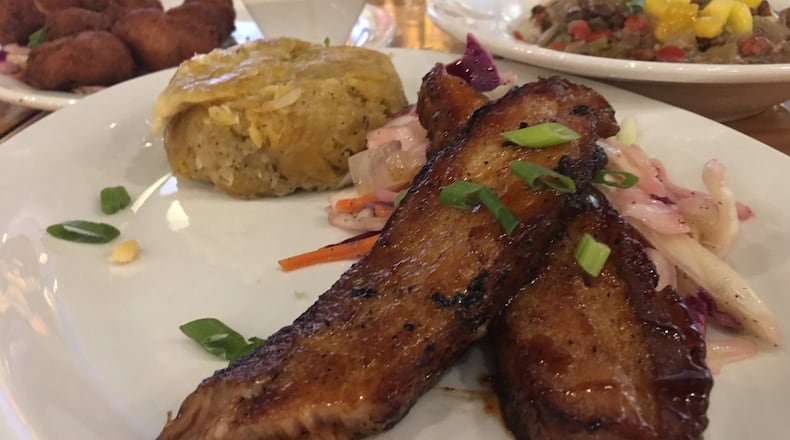 Calypso Pork Belly ($12.99) with Shrimp Pup-a-lickie ($7.49) and pigeon peas and rice ($8.99) in the background. CONTRIBUTED/ALEXIS LARSEN