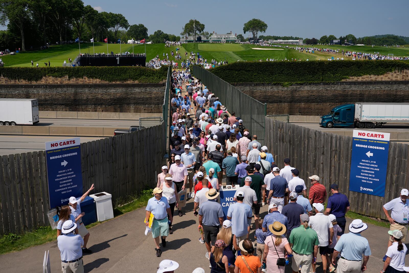 Fans use a pedestrian bridge over the Pennsylvania Turnpike, which divides Oakmont Country Club, during a practice round ahead of the U.S. Open golf tournament Wednesday, June 11, 2025, in Oakmont, Pa. (AP Photo/Carolyn Kaster)