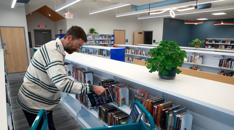 Jason Wearly, branch manager of the new Tuttle Road branch of the Clark County Library, puts books out on the shelves Tuesday, Nov. 26, 2024 as he gets ready for the library's soft opening. BILL LACKEY/STAFF