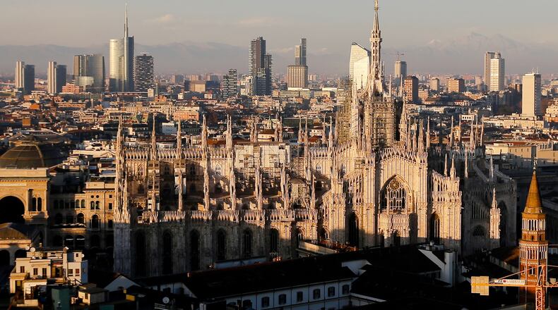 FILE - The pinnacles of the Duomo cathedral are lit by the afternoon declining sun and backdropped by the new Business Center in Milan, northern Italy, Jan. 4, 2017. (AP Photo/Luca Bruno, File)