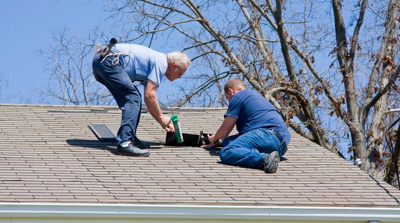 Roofing contractor repairing damaged roof on home after recent wind storms, many roofs were damaged