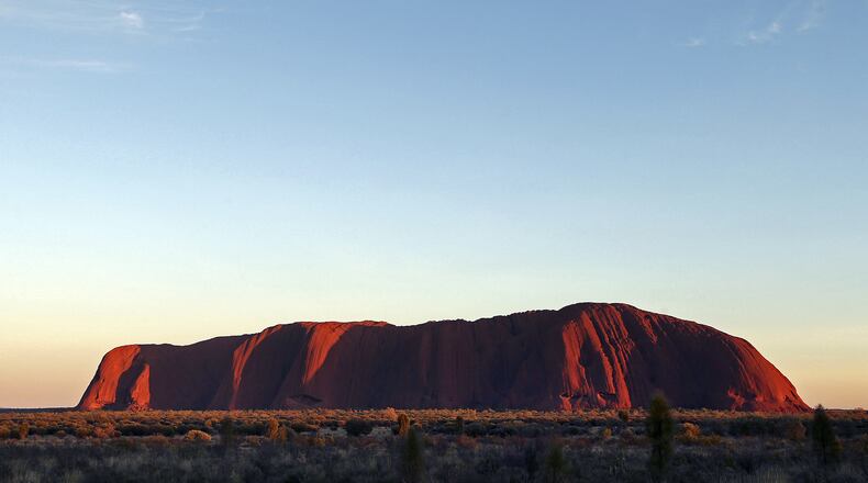 FILE - In this Tuesday, April, 22, 2014, file photo, the sun rises over Uluru, Australia. Climbing the dramatic rock formation will be banned in two years after declining visitors to the Australian scenic landmark increasingly recognize its sacredness. (AP Photo/Rob Griffith, File)