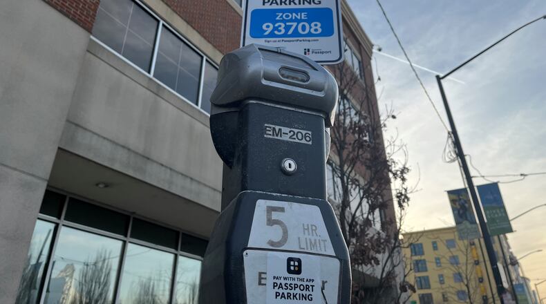 Signs have been installed around downtown Dayton advertising that people can pay for parking using the Passport Parking mobile app. But it's not operational yet. The pay-by-mobile device option is expected to formally launch in late March 2022. CORNELIUS FROLIK / STAFF