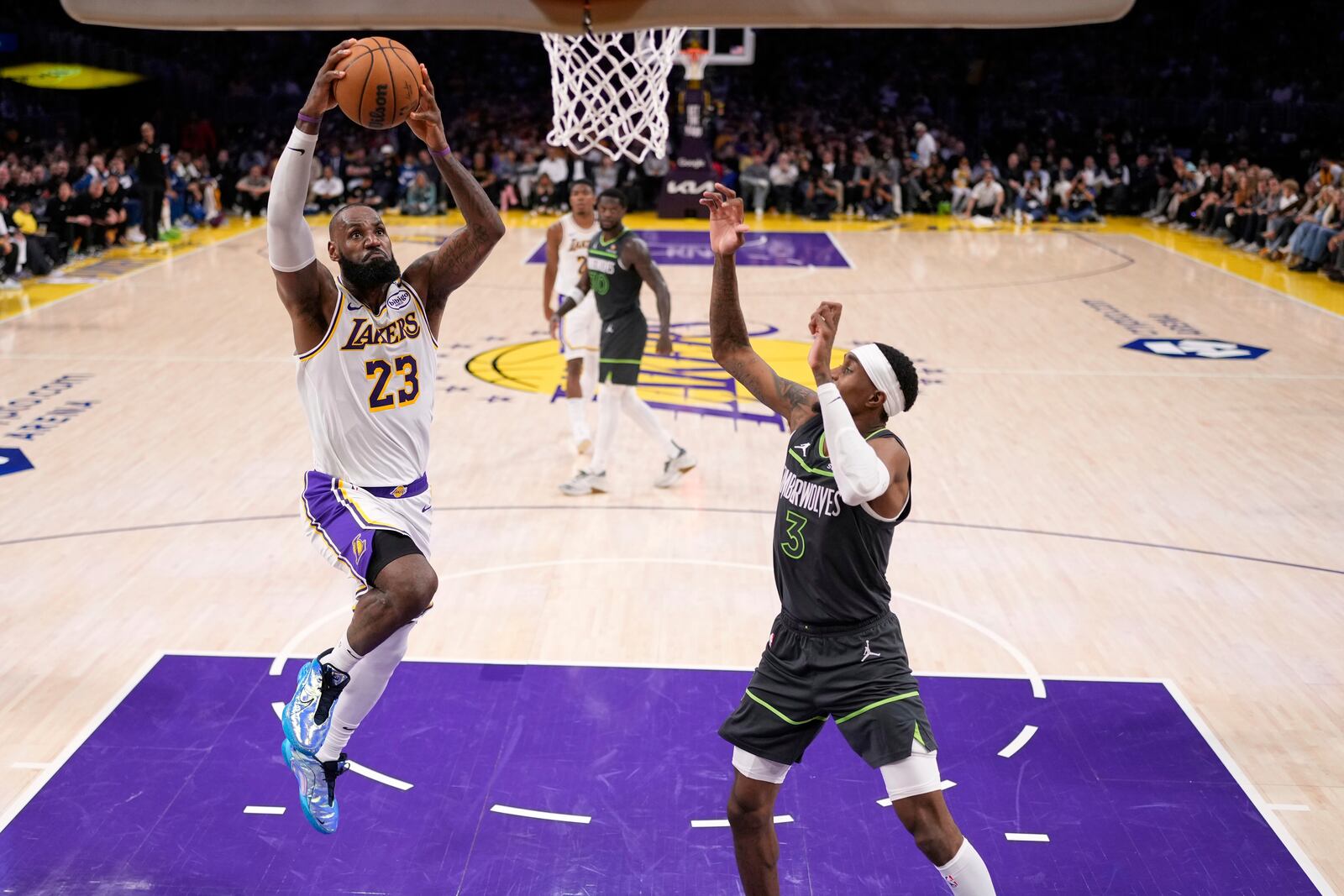 Los Angeles Lakers forward LeBron James, left, goes up for a dunk as Minnesota Timberwolves forward Jaden McDaniels, right, defends during the second half in Game 1 of an NBA first-round playoff series Saturday, April 19, 2025, in Los Angeles. (AP Photo/Mark J. Terrill)
