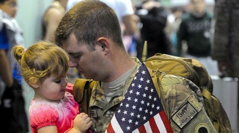 Faith Redenberger, 1, gets to know her father, Sgt. Jason Rodenberger, of Marion, Ohio, as he arrives at Rickenbacker Airport in Columbus Sunday with 240 other National Guardsmen who were stationed in Afghanistan. Staff photo by Bill Lackey