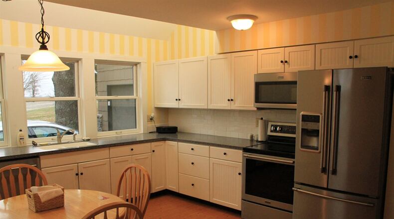 The L-shaped kitchen workspace provides long wraparound counter space with an integrated double sink under triple windows facing front. Appliances, all replaced in 2017, include the French-door refrigerator, a smooth-surface electric range, microwave oven and dishwasher.