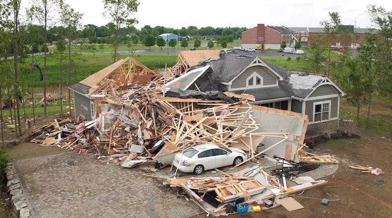 A house on Charlie Court in Brookville that was demolished by the tornado that also took the roof of the Brookville School High School Wing in the background. TY GREENLEES / STAFF