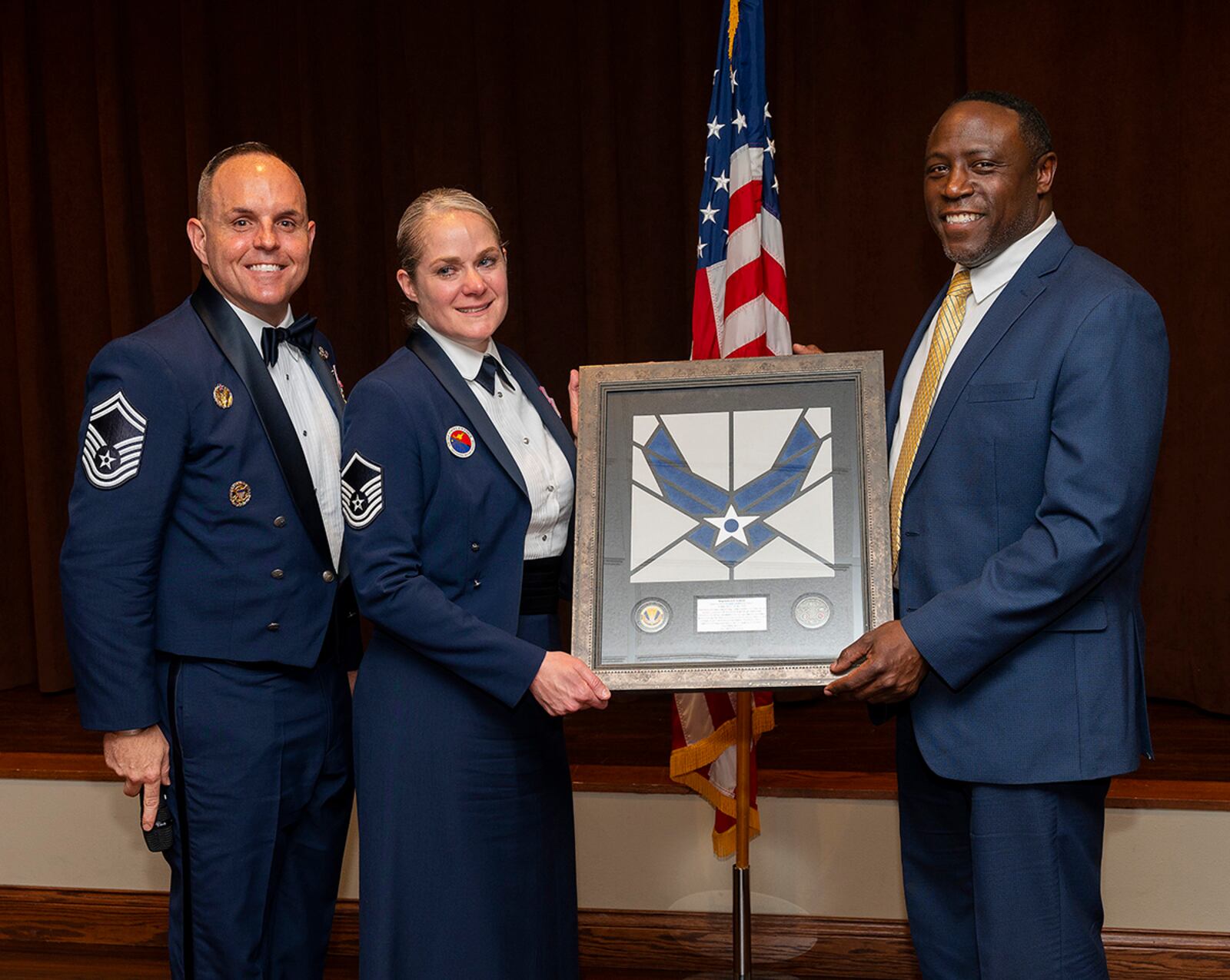 Audric Bills, 88th Force Support Squadron director, presents Master Sgt. Kelly Graham, Chief Master Sgt. Grace A. Peterson Airman Leadership School commandant, with a plaque during the school’s graduation ceremony May 5 at the Wright-Patterson Club. The graduating class was the last for Graham as she prepares to retire from the Air Force. U.S. AIR FORCE PHOTO/R.J. ORIEZ