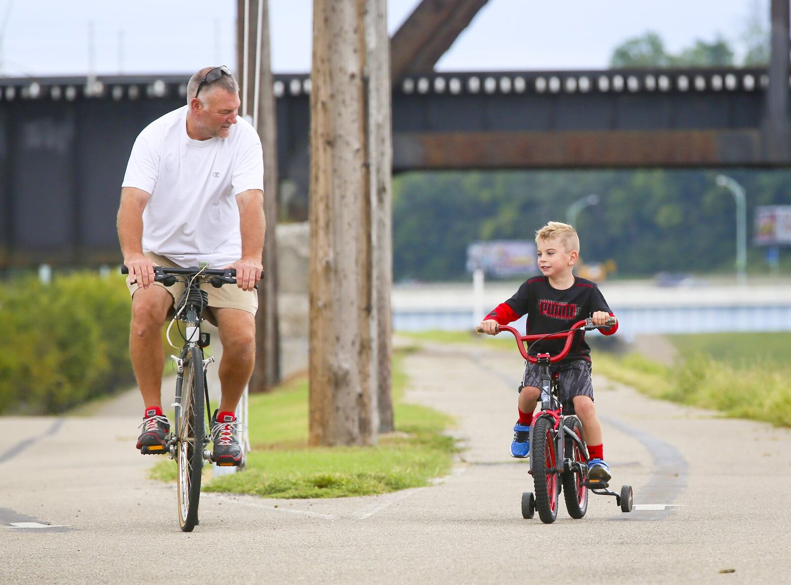 Pete Kreke and his step-grandson Brady Cecil, 5, ride along the Great Miami River bike path in September in Hamilton. GREG LYNCH / STAFF