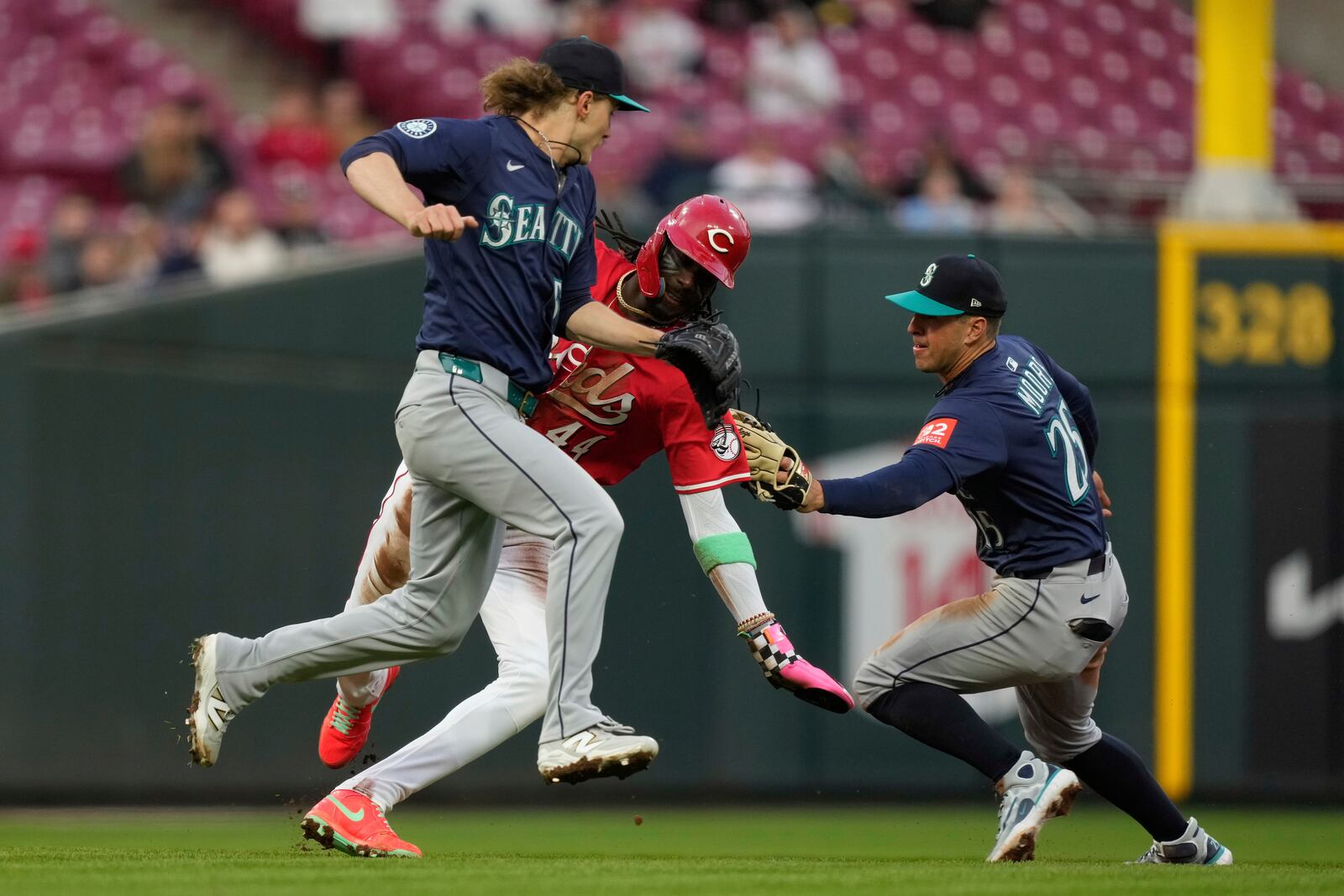 Cincinnati Reds' Elly De La Cruz, center, is tagged out trying to steal third base by Seattle Mariners second baseman Dylan Moore, right, after taking the throw from pitcher Bryce Miller, left, in the fourth inning of a baseball game, Wednesday, April 16, 2025, in Cincinnati. (AP Photo/Carolyn Kaster)