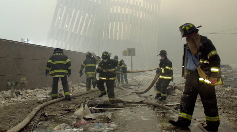 FILE - In this Sept. 11, 2001 photo, firefighters work beneath destroyed mullions, the vertical struts which once faced the outer walls of the World Trade Center towers, after a terrorist attack on the twin towers in New York. (AP Photo/Mark Lennihan, File)