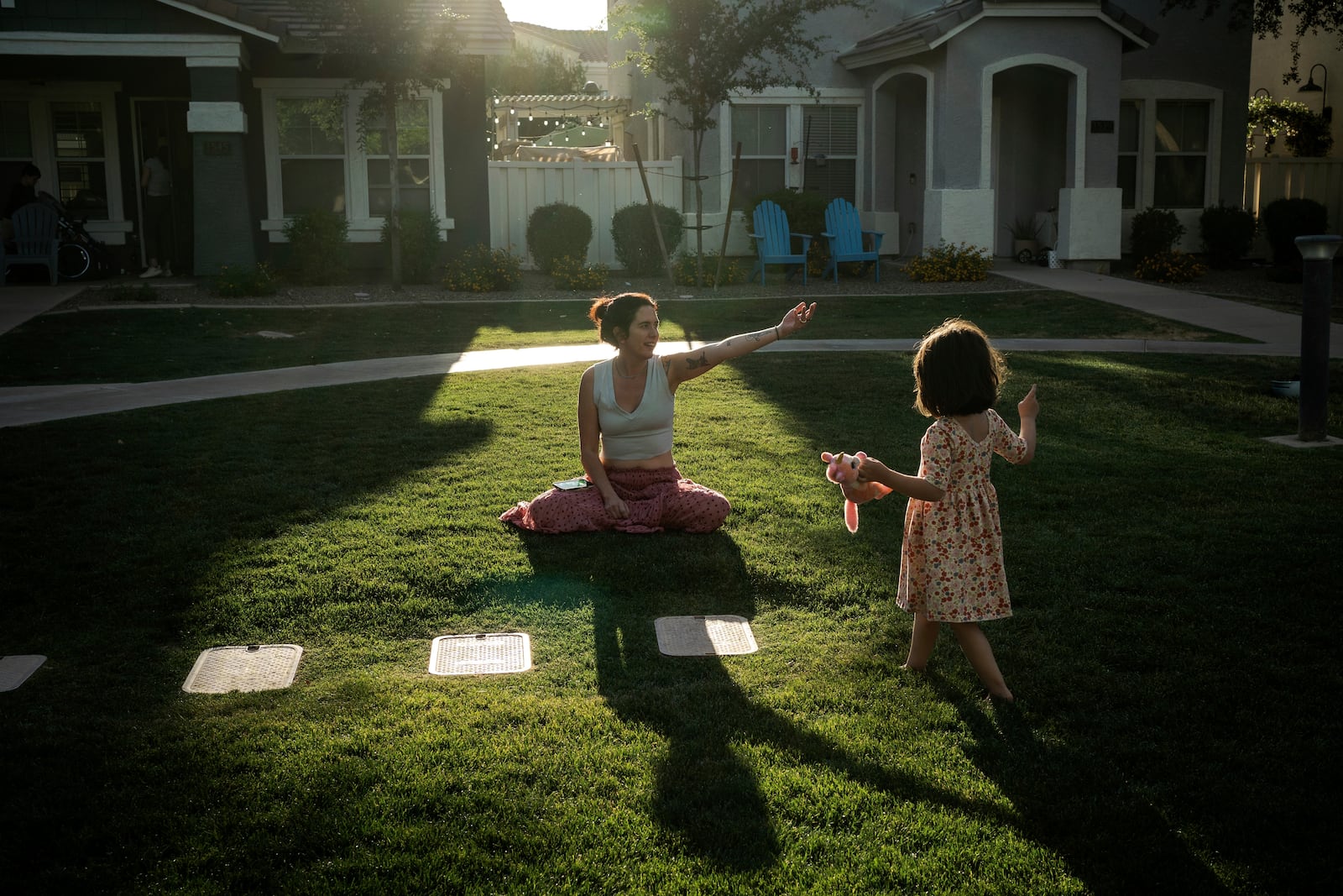 Maria Padron, center, plays with her daughter Fae Padron, 4, right, in a "kid pod," a cluster of families with more than 20 kids between them, at Agritopia, a community nestled around a plot of agricultural land, April 21, 2025, in Gilbert, Ariz. (AP Photo/Annika Hammerschlag)