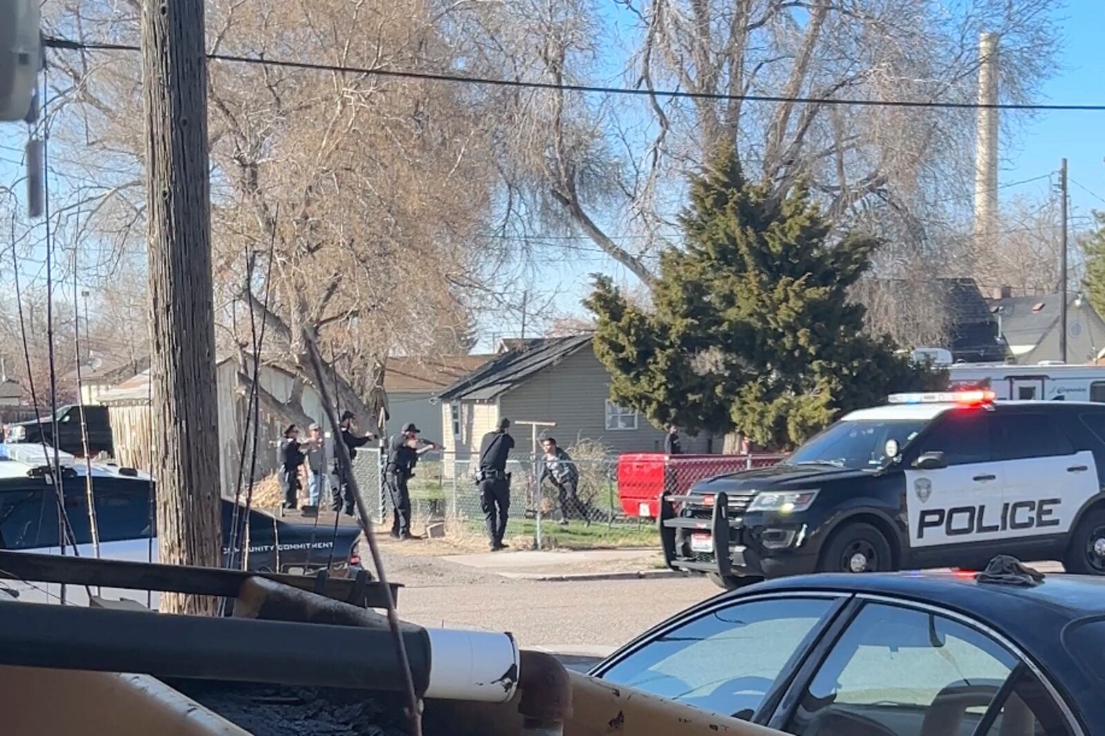 In this image taken from video, police are seen shortly before opening fire on a teen on the other other side of a fence Saturday, April 5, 2025, in Pocatello, Idaho. (Brad Andres via AP)
