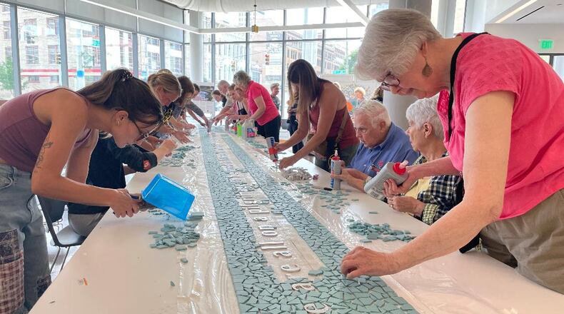 Community volunteers gathered July 11 at the Dayton Metro Library to finish the creation of the 8/4 Memorial mosaic. PHOTO BY RUSSELL FLORENCE JR.