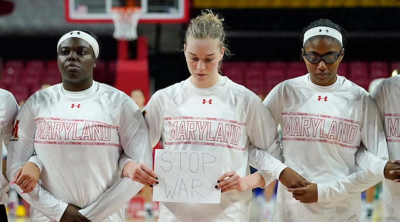 Maryland guard Taisiya Kozlova, center, holds a sign reading "No War" while standing with guard Ashley Owusu, left, and guard Shyanne Sellers, right, prior to a college basketball game against Florida Gulf Coast in the second round of the NCAA tournament, Sunday, March 20, 2022, in College Park, Md. (AP Photo/Julio Cortez)