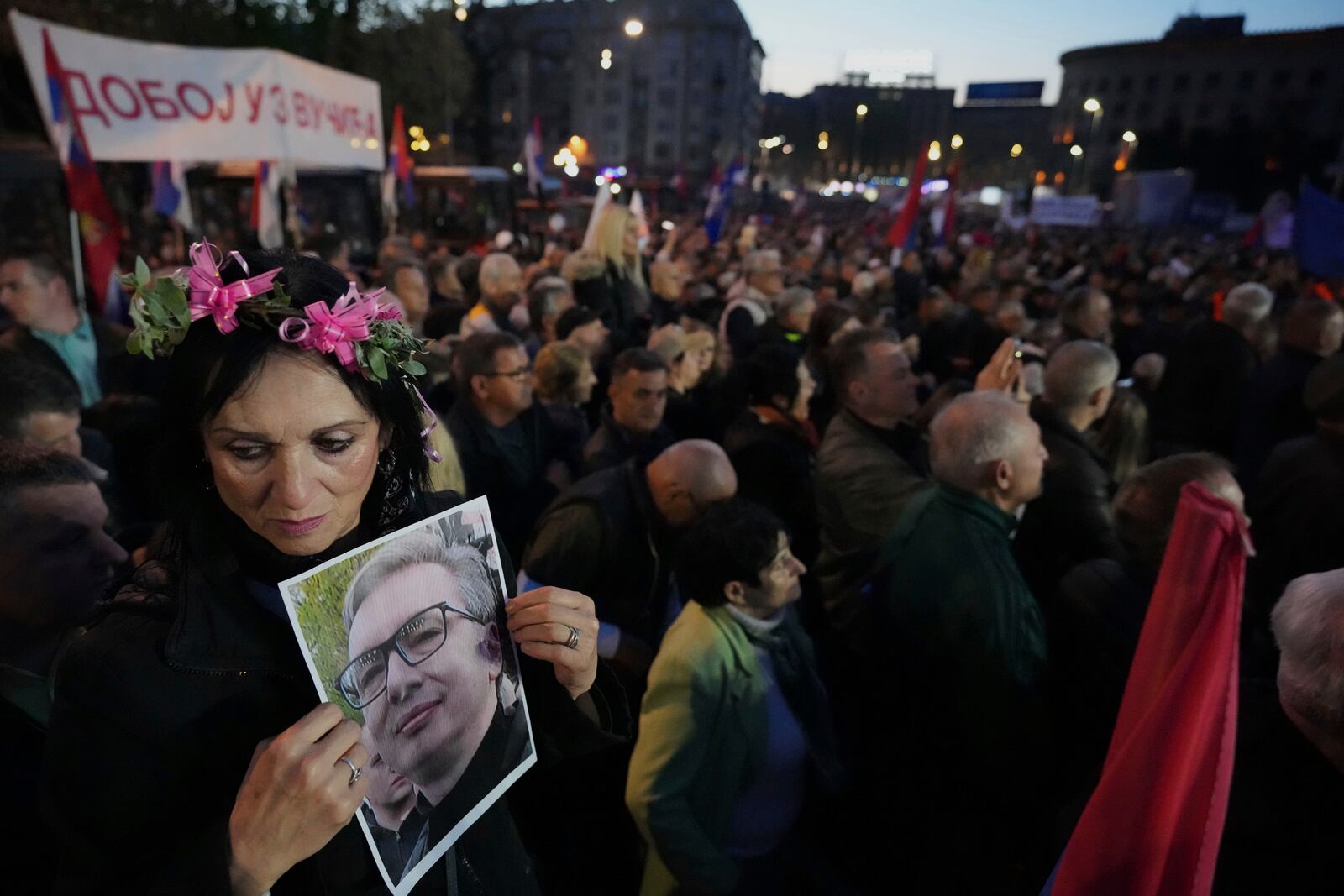 A supporter of Serbia's President Aleksandar Vucic holds his photo during a rally, apparently designed to counter student-led gatherings, in Belgrade, Serbia, Saturday, April 12, 2025. (AP Photo/Darko Vojinovic)
