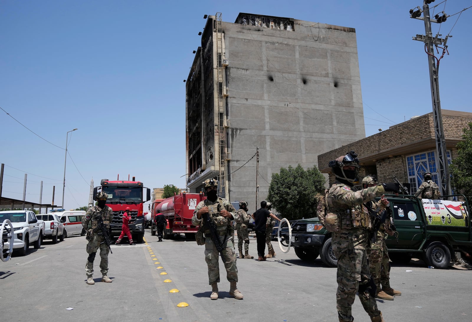Iraqi Security forces gather in front of a burning hypermarket building in Kut, Iraq, Thursday, July 17, 2025. (AP Photo/Hadi Mizban)