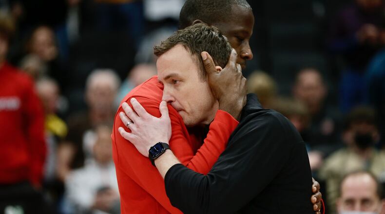 Dayton coach Anthony Grant hugs Massachusetts coach Matt McCall, who coached his final game in a loss to Dayton, in the postgame handshake line on Friday, March 11, 2022, in the quarterfinals of the Atlantic 10 Conference tournament at Capital One Arena in Washington, D.C. David Jablonski/Staff