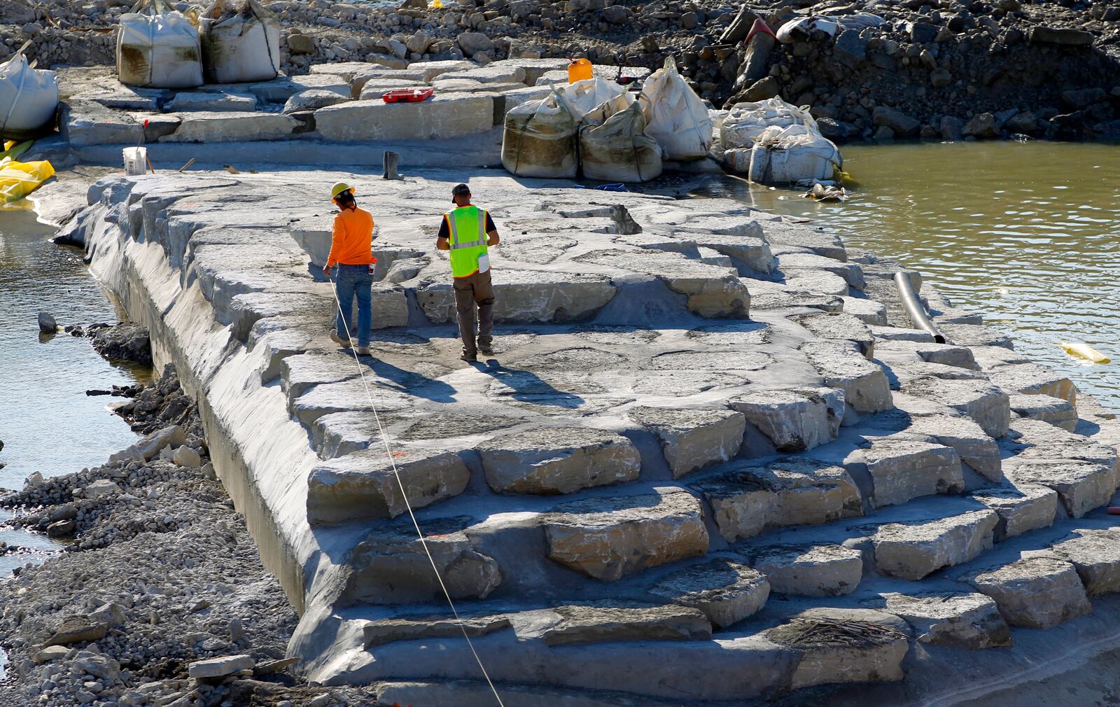 Construction continues on the $4 million RiverScape River Run project at the former Monument Avenue low dam in Dayton. Limestone boulders are anchored in the low dam foundation which will create boating passages and span across the Great Miami River. When the Monument Avenue dam portion of the project is finished, contractors will begin work upriver to construct a second dam-like structure with limestone boulders that have similar passages one with fast water for expert boaters, the other with slower flow for the less experienced.  LISA POWELL / STAFF