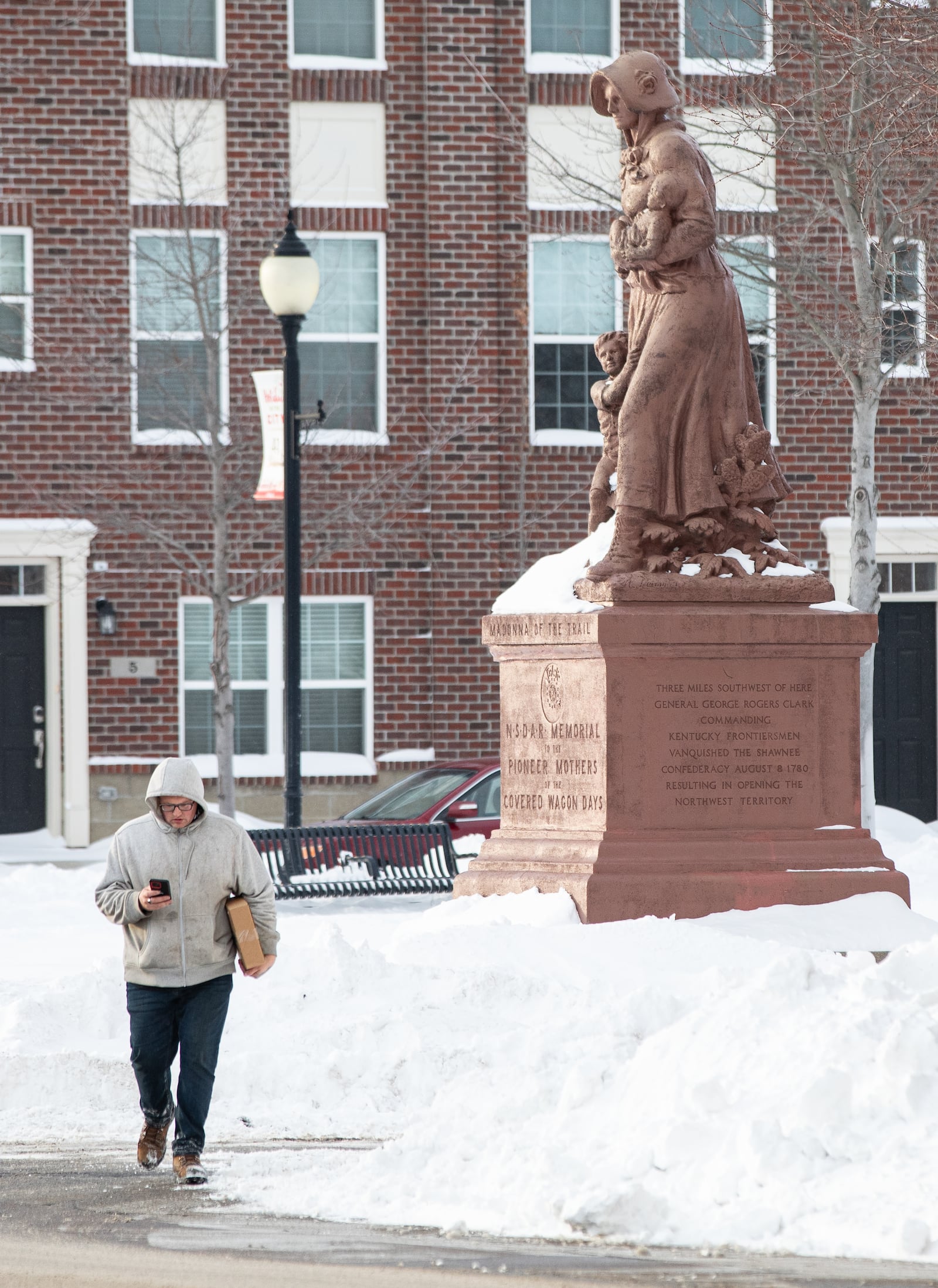 A man walks on West Main Street by the Madonna of the Trail statue in National Road Commons Park on Tuesday, Jan. 27. The city received 13 inches of snow over the weekend. BRYANT BILLING./STAFF