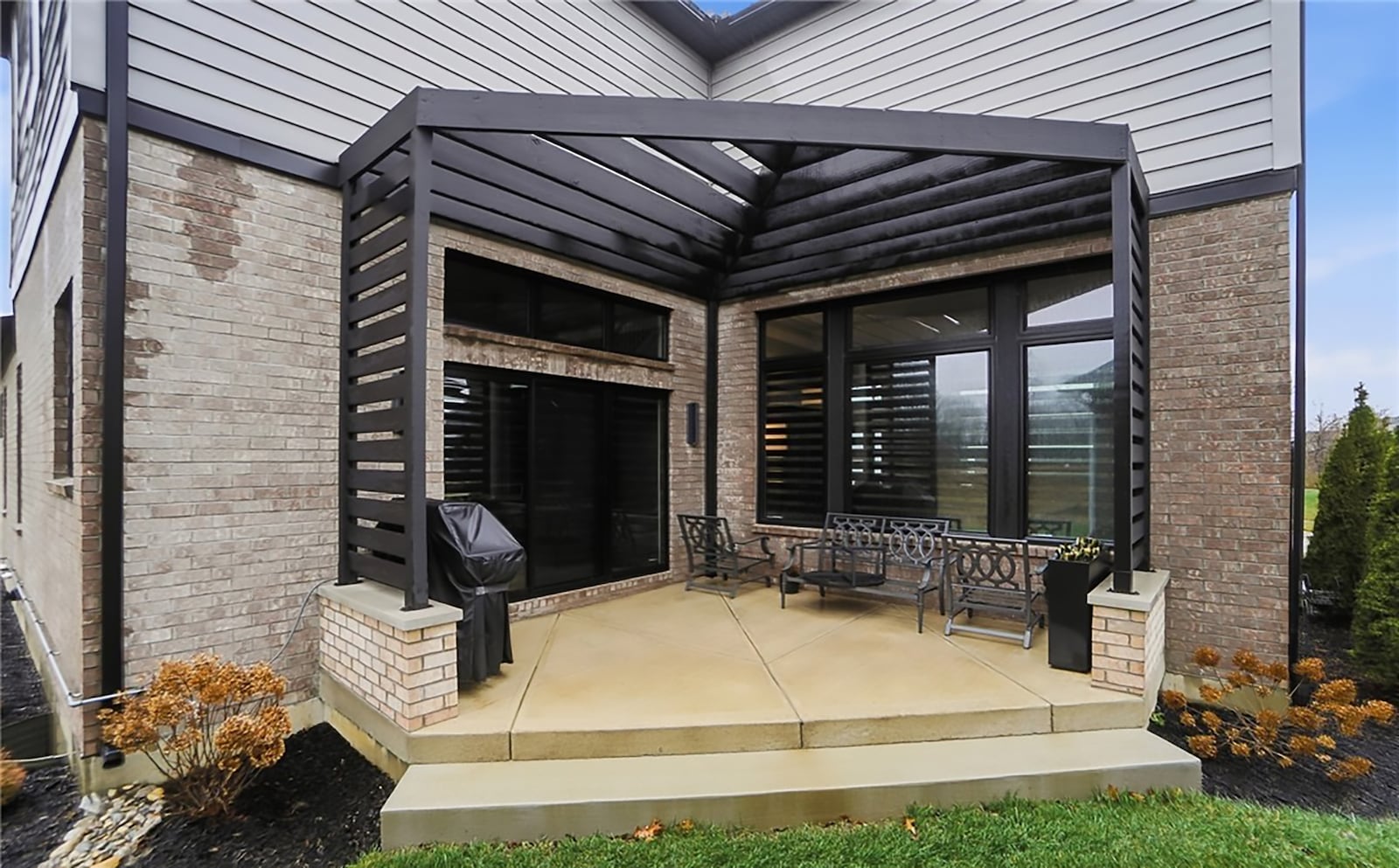 The concrete patio off the kitchen has brick walls on both sides and a wood pergola. CONTRIBUTED