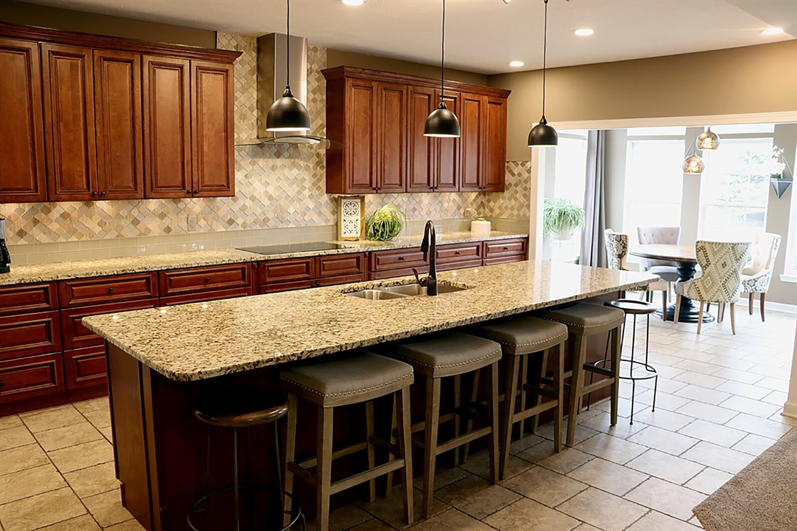 A long island that can seat 8 is the centerpiece to the kitchen as cherry cabinetry with complementing granite countertops fills one wall and wraps around wall ovens and appliances. The island has a double sink, built-in dishwasher and wine cooler and has hanging lights above. CONTRIBUTED PHOTO BY KATHY TYLER
