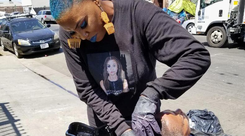 This photo provided by Melissa Acedera shows Shirley Raines washing a person's hair in Skid Row, 2018, in Los Angeles. (Melissa Acedera via AP)