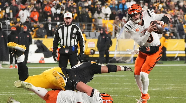 Cincinnati Bengals quarterback Joe Burrow (9) avoids Pittsburgh Steelers defensive tackle Cameron Heyward (97) with Cincinnati Bengals guard Cordell Volson (67) during the second half of an NFL football game in Pittsburgh, Saturday, Jan. 4, 2025. (AP Photo/Gene J. Puskar)