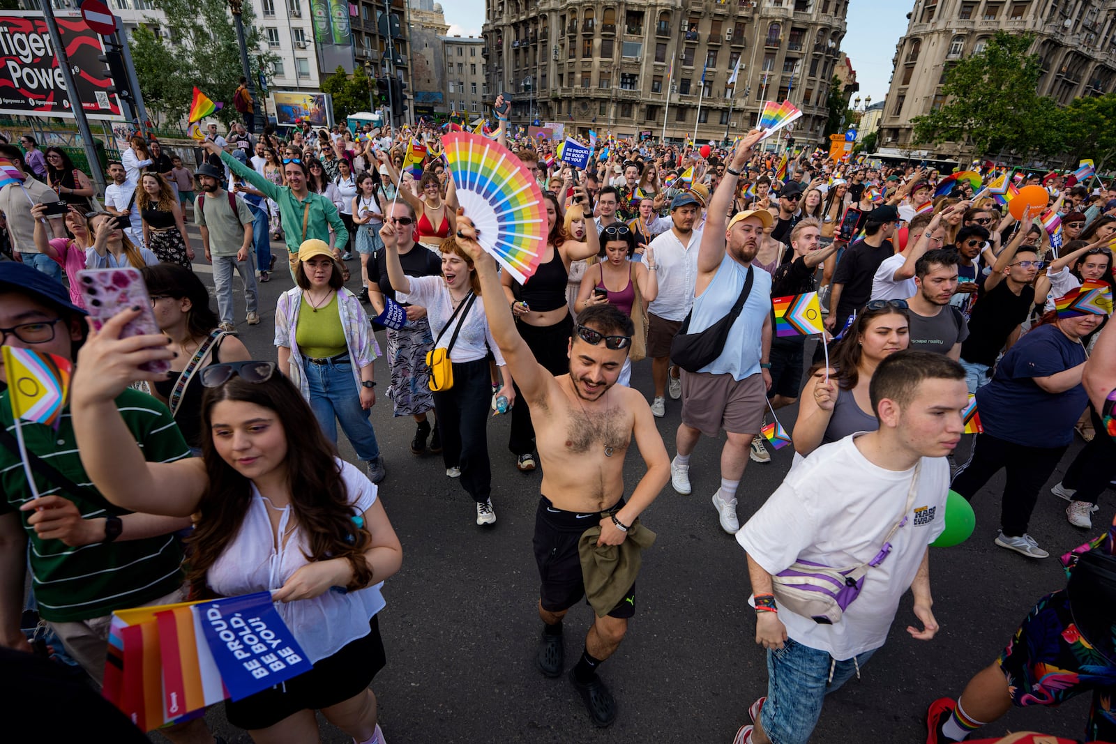 People dance while holding rainbow flags during the Bucharest Pride Parade, in Bucharest, Romania, Saturday, June 7, 2025. (AP Photo/Andreea Alexandru)