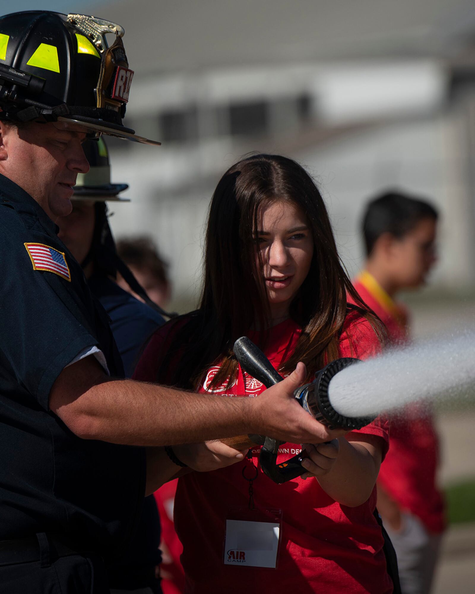 A camper handles a fire hose with the help of firefighter Thomas Trost, 788th Civil Engineer Squadron, at the Wright-Patterson Air Force Base main fire station June 15. U.S. AIR FORCE PHOTO/R.J. ORIEZ